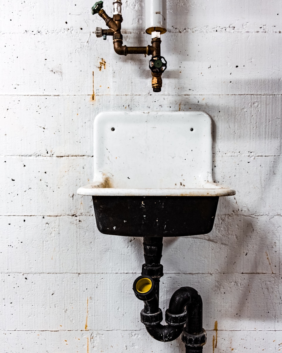 white and black sink beside wall symbolizing water damage