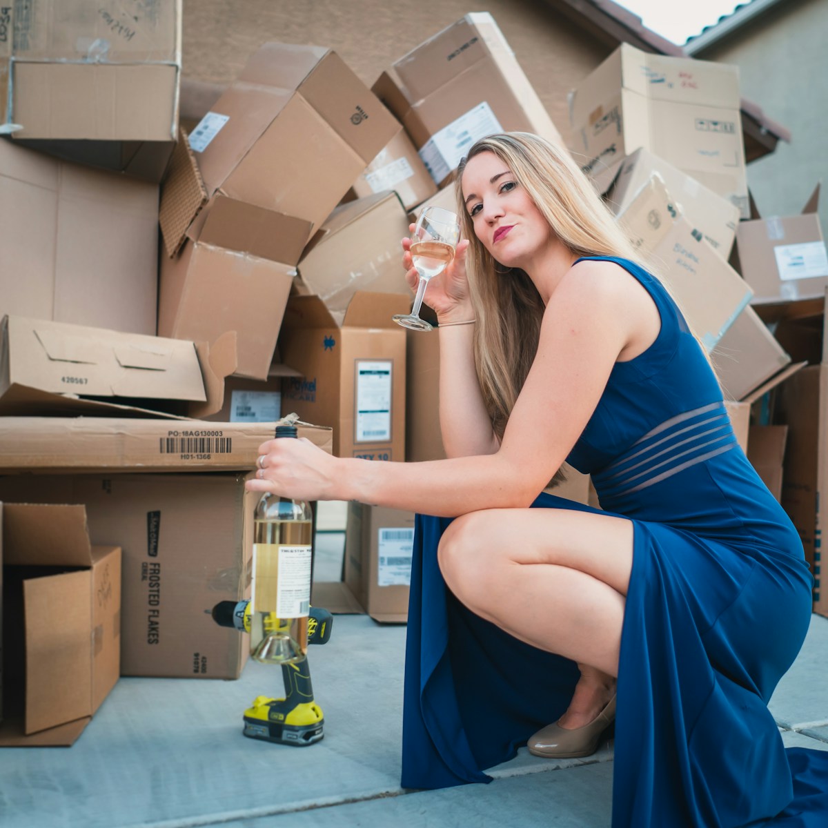 woman in blue sleeveless dress sitting on brown cardboard box with homeowners insurance